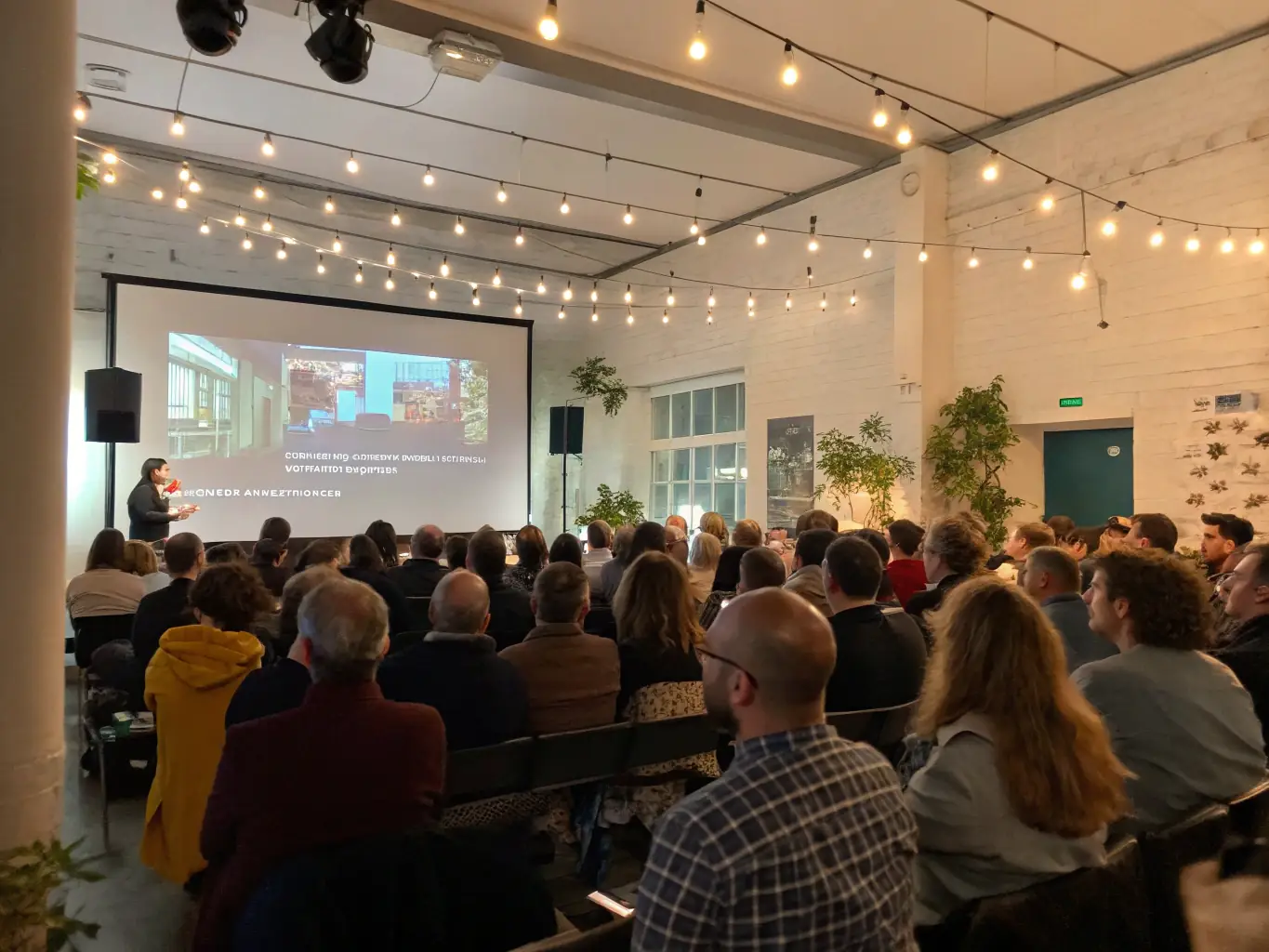A vibrant scene from a film screening event hosted by APC ASSOCIATION POUR LE CINEMA, showing a diverse audience engaged in a post-screening discussion.